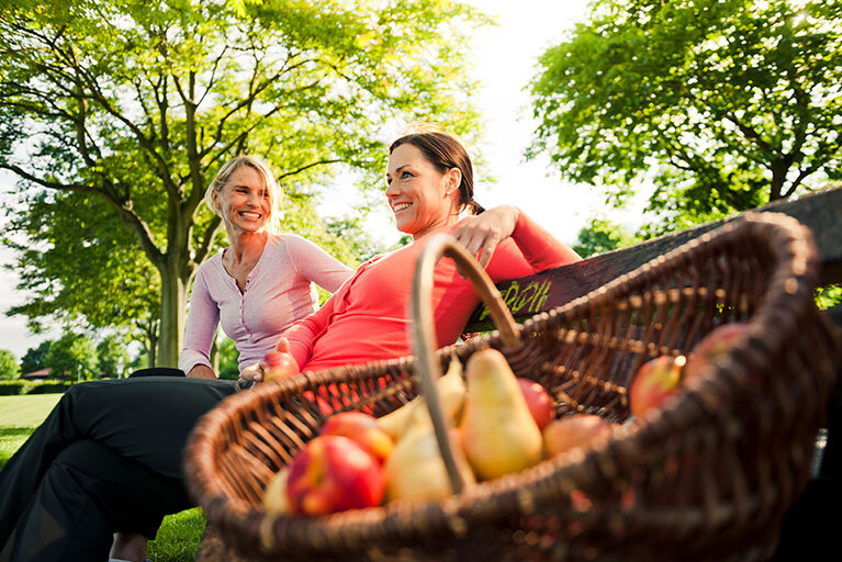 zwei Frauen sitzen mit einem Obstkorb auf der Bank 