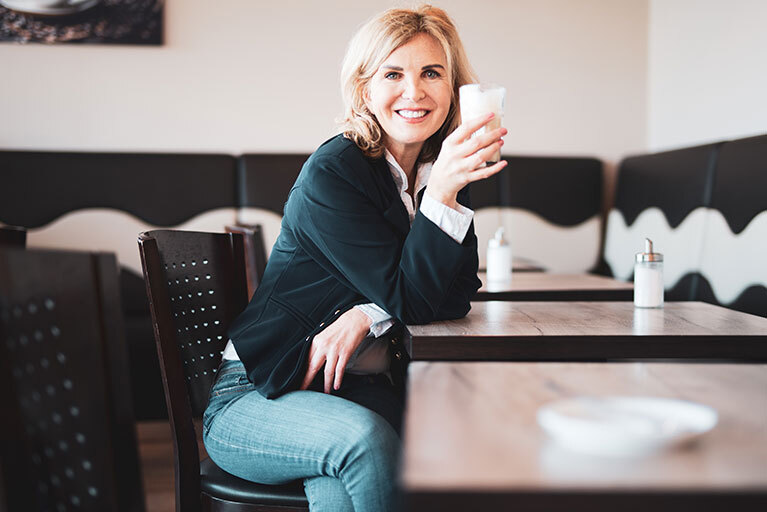 Hormonersatztherapie: Frau sitzt am Tisch und trinkt Kaffee