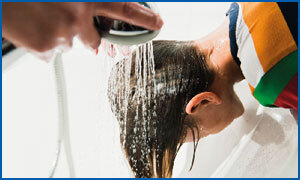 Das Foto illustriert die Anwendung des Kopfläuse-Mittels Licener von Hennig. Einem Jungen, bei dem das Mittel Licener bereits lange genug in Haare und Kopfhaut eingewirkt ist, wird das Mittel mit der Duschbrause aus den Haaren gespült.