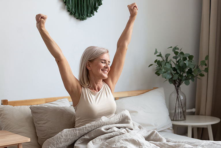 Schlafqualität verbessern: Frau streckt sich im Bett