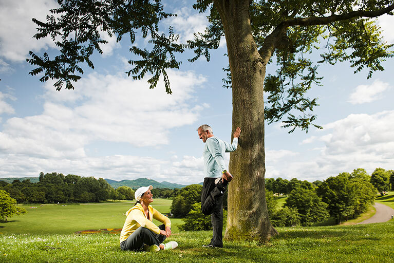Mann und Frau machen Pause vom Laufen an einem Baum
