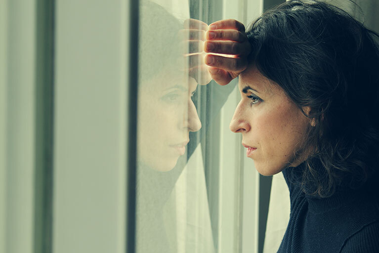 Frau schaut ernst aus dem Fenster