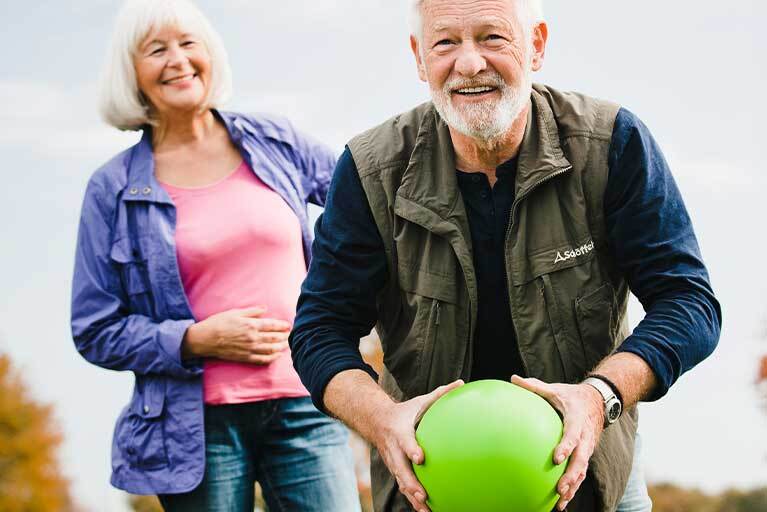 Gleichgewichtsübung: Älteres Paar spielt mit Ball