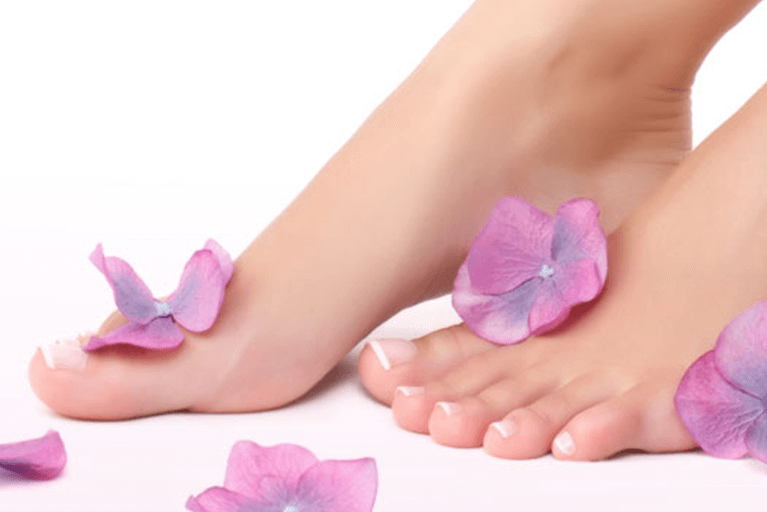 Blütenblätter auf nackten Füßen einer Frau